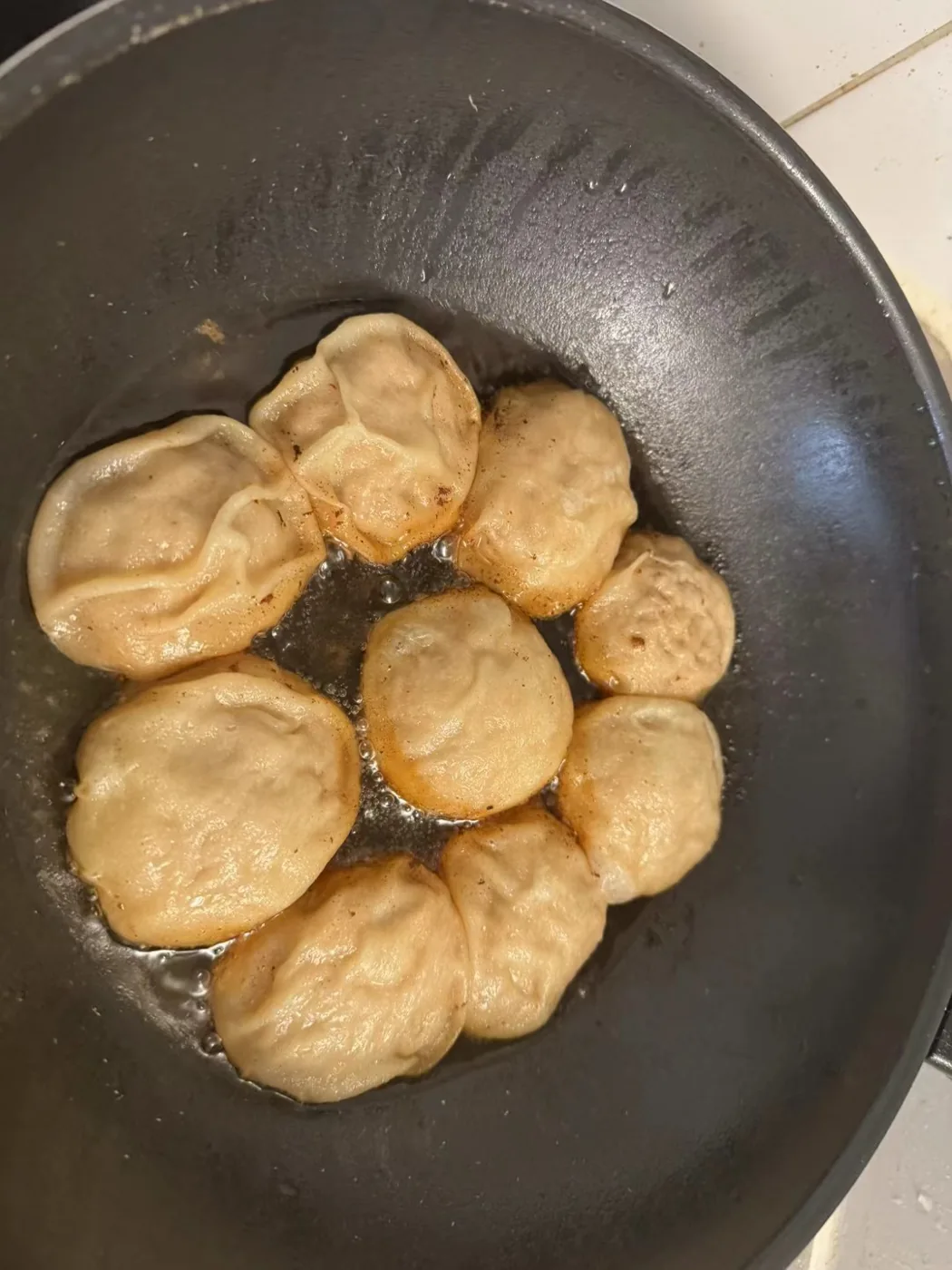 Homemade Shanghai shengjian, pan-fried buns cooking in a pan